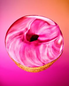 a donut with pink icing on a pink background