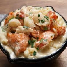 a black bowl filled with pasta and shrimp