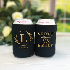 two black and gold can coolers sitting on top of a table next to flowers