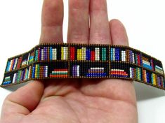 a hand is holding a colorful bracelet made out of bookshelves on it's side