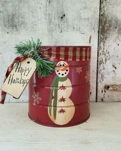 a red tin can with a snowman on it and a happy holidays tag hanging from the top