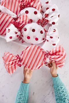 a person is wrapping presents in red and white paper with polka dots on the top