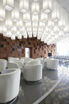 a room filled with lots of white chairs next to a wall covered in wooden blocks