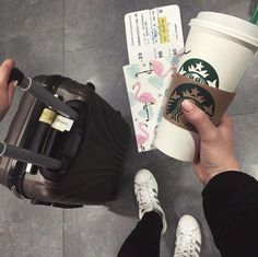 a person holding a starbucks cup and luggage