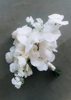 a bouquet of white flowers sitting on top of a gray table next to a wall