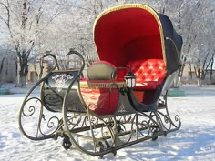 a horse drawn carriage in the snow with red cushions on it's seat and back