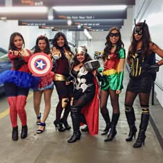 several women dressed up as superheros posing for a photo in an underground parking garage