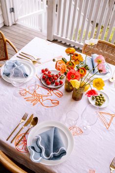 the table is set with plates, silverware and flowers in vases on it