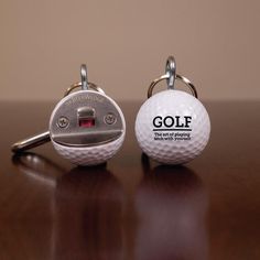 two golf ball shaped keychains on a table with the words eagle, rude, bogey and beer printed on them