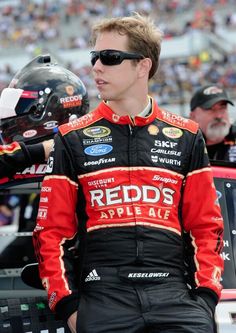 a man standing next to a race car in front of a crowd