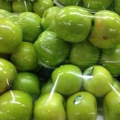 many green apples are wrapped in plastic