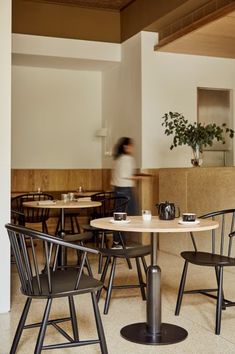 a person sitting at a table in a room with tables and chairs around it,