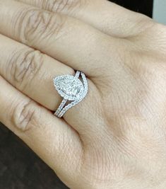 a woman's hand with a diamond ring on top of her finger and the other hand holding an engagement ring