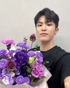 a young man holding a bouquet of purple flowers