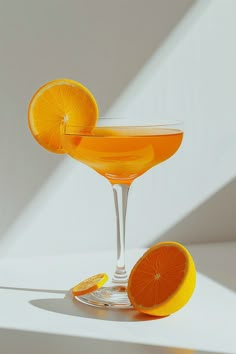 two orange slices sit on the rim of a cocktail glass with an orange slice in it