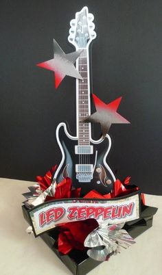 an electric guitar is sitting in a box with red flowers and ribbon around the neck