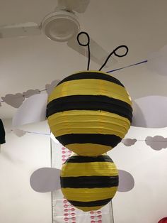 a yellow and black paper ball hanging from the ceiling with scissors in it's center