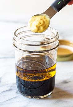 a spoon with some food in it on top of a glass jar filled with liquid