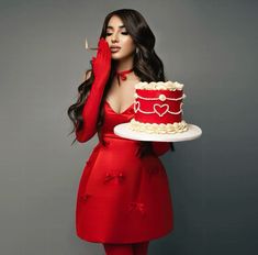 a woman holding a knife in front of a red cake on a white platter