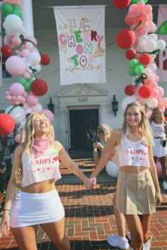 two young women holding hands in front of balloons