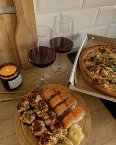 a table topped with two pizzas next to glasses of wine and plates of food