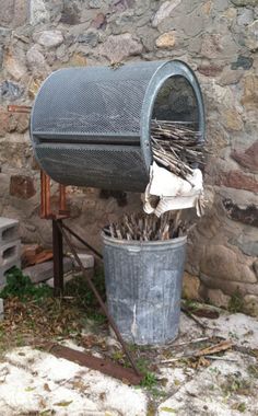 an old metal mailbox sitting on top of a stone wall next to a trash can