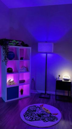 a living room with purple lighting on the walls and wooden flooring in front of a white bookcase