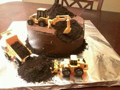 there is a chocolate cake with construction trucks on the top and dirt in the middle