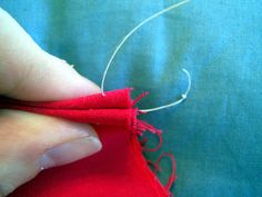 someone is stitching something with red thread