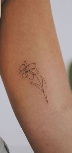 a woman's arm with a single flower tattoo on the left side of her arm