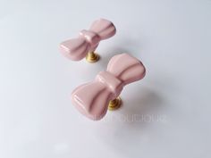 two pink bow shaped knobs on white surface