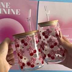 two people holding up glass mugs with cherries and bows on them, in front of a magazine