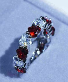 a red and white diamond ring sitting on top of a table