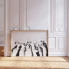 three wine glasses are placed in front of a framed photograph on the floor next to an empty wall