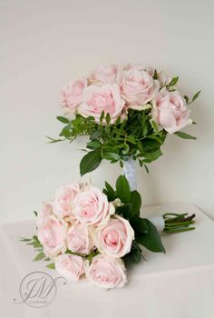 a bouquet of pink roses sitting on top of a white table