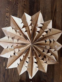 an origami flower made out of brown paper on top of a wooden table