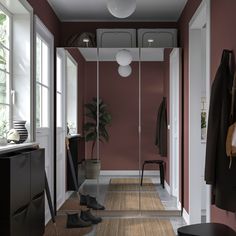 an empty hallway with red walls and white trim on the doors, carpeted flooring and black furniture