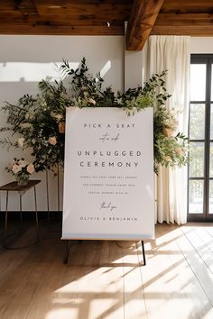 an unplugged ceremony sign in front of a window with flowers and greenery