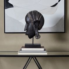 a table with a black sculpture on top of it next to a book shelf and a painting