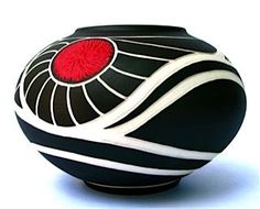 a black vase with red and white designs on the top is sitting in front of a white background