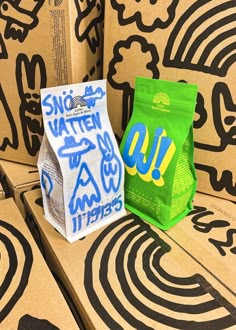 two bags of food sitting on top of cardboard boxes with graffiti written on the sides