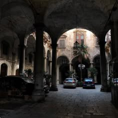 two cars are parked in the middle of an old building with columns and arches on both sides