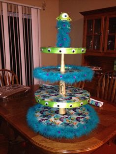 three tiered cake decorated with blue feathers and monsters