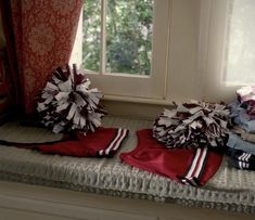 two cheerleader pom poms sitting on top of a bed next to a window