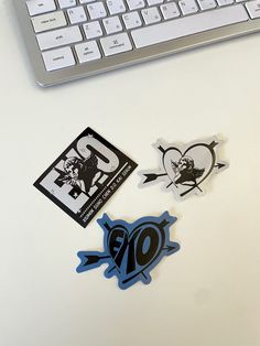 three stickers on a desk next to a keyboard