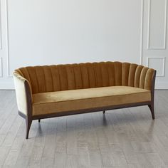 a brown and tan couch sitting on top of a hard wood floor next to a white wall