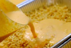 a person pouring orange juice into a pan filled with oatmeal