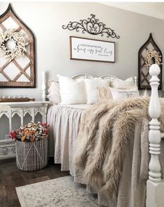 a white bed sitting in a bedroom next to a wooden dresser and mirror on the wall