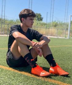 a young man sitting on top of a soccer field