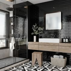 a black and white tiled bathroom with a large mirror above the sink, shower stall and toilet